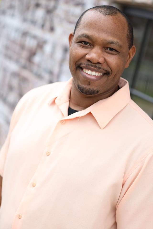 Chris Davios smiling warmly in a peach shirt